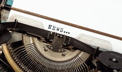 Closeup of typewriter ribbon, on a blank sheet the word NEWS, concept