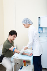 Obraz premium the nurse is going to loosening a tourniquet during the injection. intravenous injection it may be contrast administration for MRI or drugs or a fence of tests for diseases. coronavirus covid 19