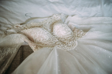 Morning of the bride: the wedding dress is lying on the bed - 335907731