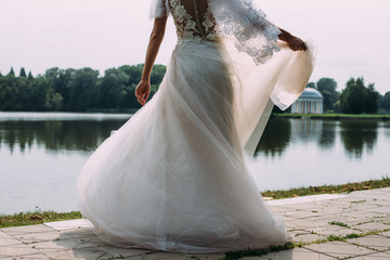 The bride twirls in a wedding dress with a train on the background of the lake - 335908109