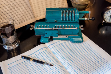An old mechanical calculator, an arithmetic counter, accounting books, a watch, and a pen on a...