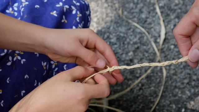 H&auml;nde einer Frau flechten Bastfasern zu einem Zopf