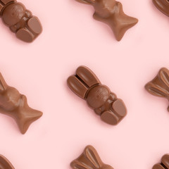 Easter bunny shaped sweets of milk chocolate laying in rows on pink background.Religious holiday composition,rabbit pattern for congratulations in greeting card.Symbol of celebration Sunday of Christ