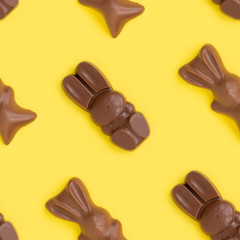 Easter bunny shaped sweets of milk chocolate laying in rows on yellow background.Religious holiday composition,rabbit pattern for congratulations, greeting card.Symbol of celebration Sunday of Christ