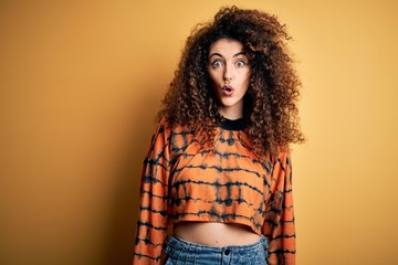 Young beautiful brunette woman with curly hair and piercing wearing casual t-shirt afraid and shocked with surprise expression, fear and excited face.