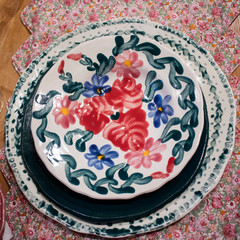 Porcelain white dish in red and blue flowers on red brocade on table