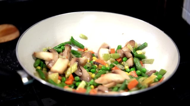 Preparation of vegetables in a pan. Mixing vegetables with wooden shoe.