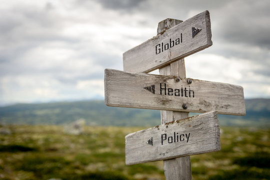 Global, Health And Policy Text On Wooden Signpost Outdoors In Nature. Coronavirus, Politics And World Problems Concept.