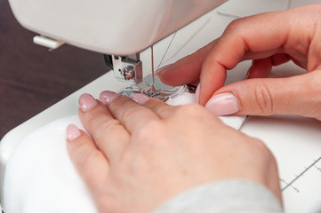 A woman sews a self-made protective face mask