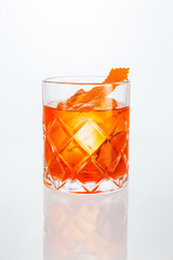 Close up of a hand holding a glass of negroni cocktail on white background with copy space.
