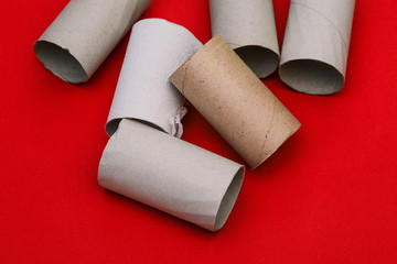 Cardboard tubes from toilet paper. Remains of toilet paper on a red background.