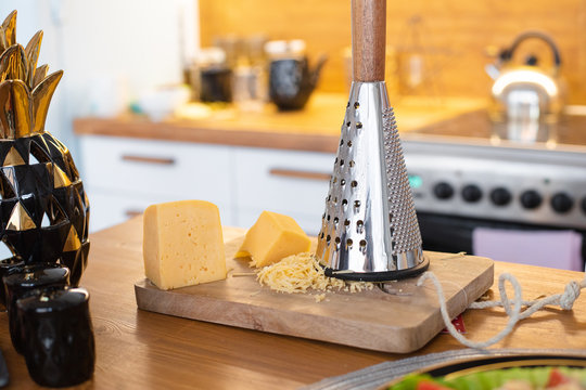 Cheese is on the table near the iron grater, picture of a dinner rable