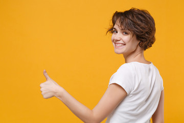 Back rear view of smiling young brunette woman girl in white t-shirt posing isolated on yellow...