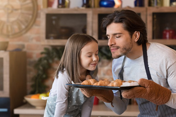 Homemade pastries. Cute little girl and dad smelling freshly baked croissants