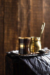 Turkish coffee cup with vintage copper stovetop coffee pot shot on a dark textured wooden background backlit 