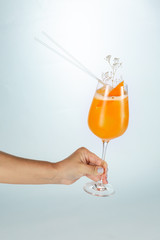 Close up of a hand holding a glass of Singapore cocktail on white background with copy space.
