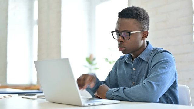 Young African Man Thinking and working on Laptop
