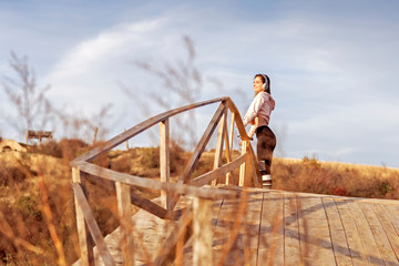 On wooden bridge young fit woman relax after jogging in the nature
