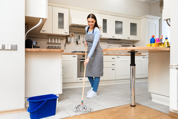 Fototapeta na wymiar Young woman using mop to clean floor