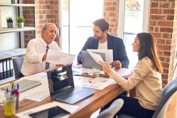 Group of business workers working together. Sitting on desk using laptop reading documents at the office