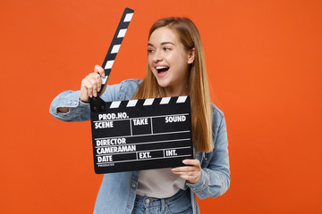 Cheerful young woman girl in casual denim clothes posing isolated on orange wall background studio...