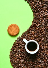 Coffee composition of a Cup with coffee and coffee beans on a green background. Coffee mood.