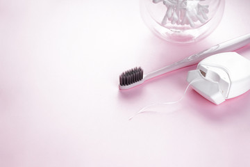 Toothbrush and dental floss with space for text on a pink background