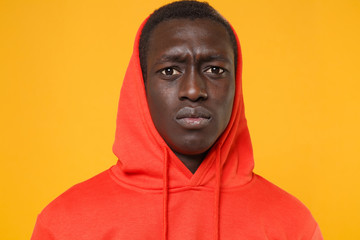 Close up of perplexed young african american man guy in red streetwear hoodie with hood on head posing isolated on yellow wall background. People lifestyle concept. Mock up copy space. Looking camera.