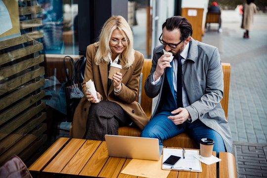 Two business people working and eating together