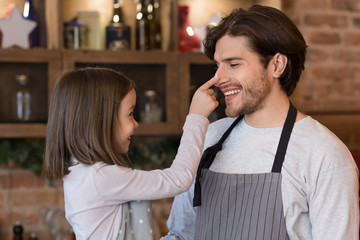 Little girl having fun with dad while baking together in kitchen