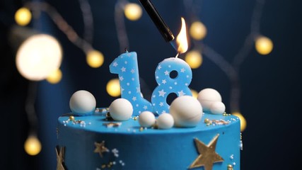 Birthday cake number 18 stars sky and moon concept, blue candle is fire by lighter and then blows out. Copy space on right side of screen if required. Close-up and slow motion