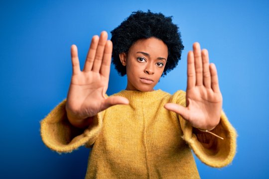 Young beautiful African American afro woman with curly hair wearing yellow casual sweater doing frame using hands palms and fingers, camera perspective