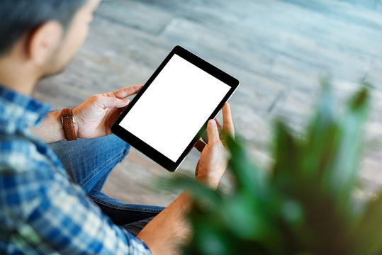 Mockup of a man holds tablet computer with isolated screen in his hands. View from above. Clipping path.