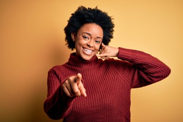 Young beautiful African American afro woman with curly hair wearing casual turtleneck sweater...