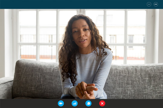 Computer Screen View African Woman Sit On Couch Looking At Webcam, Share News With Friend, Applicant Pass Job Interview By Videoconference App, Communicates With Employer From Home, Video Call Concept