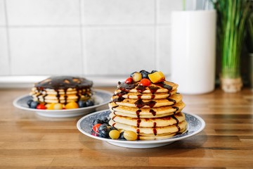 Pancakes with berries on plates in kitchen