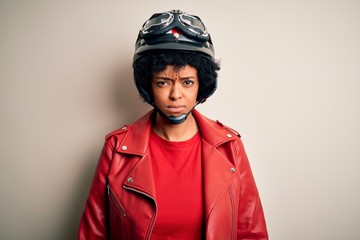 Young African American afro motorcyclist woman with curly hair wearing motorcycle helmet skeptic and nervous, frowning upset because of problem. Negative person.