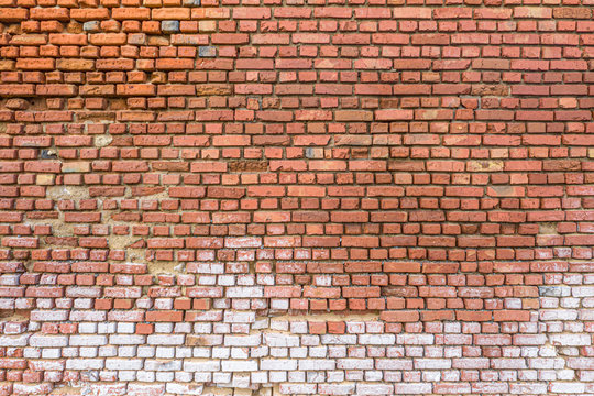 Red brick wall partially destroyed by rain. Texture.