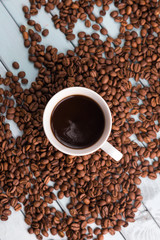 Coffee beans are spilled on a wooden table. Coffee Cup on the turquoise table. Still life with coffee.