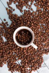 Coffee beans are spilled on a wooden table. Coffee Cup on the turquoise table. Still life with coffee.