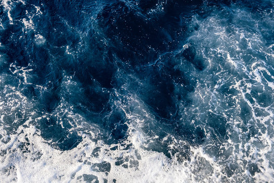 Top down aerial view of sea water surface. White foam waves texture as natural background.