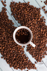 Naklejka premium Coffee beans are spilled on a wooden table. Coffee Cup on the turquoise table. Still life with coffee.