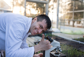 Agronomist working with microscope in greenhouse