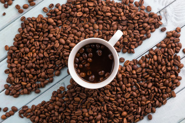 Coffee beans are spilled on a wooden table. Coffee Cup on the turquoise table. Still life with coffee.