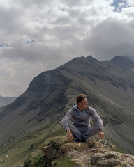 Young man meditates on the top of Alpine mountains.