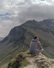 Naklejka premium Young man meditates on the top of Alpine mountains.