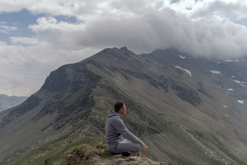 Fototapeta premium Young man meditates on the top of Alpine mountains.
