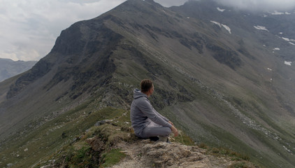 Fototapeta premium Young man meditates on the top of Alpine mountains.