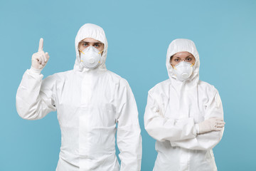 Fototapeta premium People in protective suits respirator masks isolated on blue background studio. Epidemic new rapidly spreading coronavirus 2019-ncov originating in Wuhan China virus concept pointing fingers copyspace