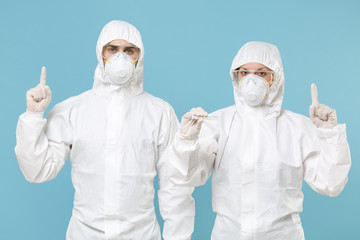 Two people in protective suits respirator masks hold in hand thermometer isolated on blue background studio. Epidemic pandemic new rapidly spreading coronavirus 2019-ncov, medicine flu virus concept.